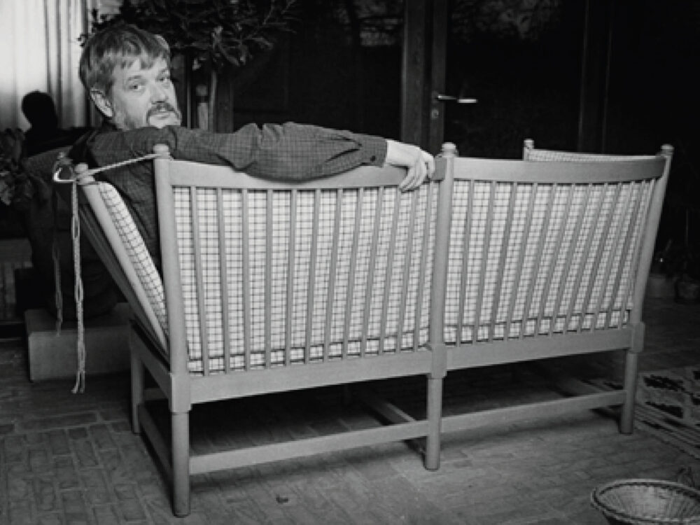 Børge Mogensen lehnt sich auf seinem legendären, 1945 entworfenen und anfänglich von Fritz Hansen hergestelltem Spoke-Back Sofa zurück
